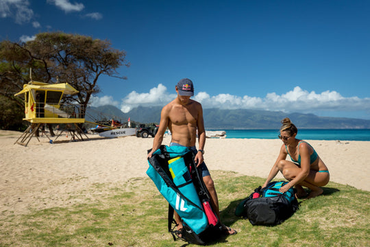 Two Paddleboarders on the beach opening Fanatic Fly Air Pocket Paddleboard Bags