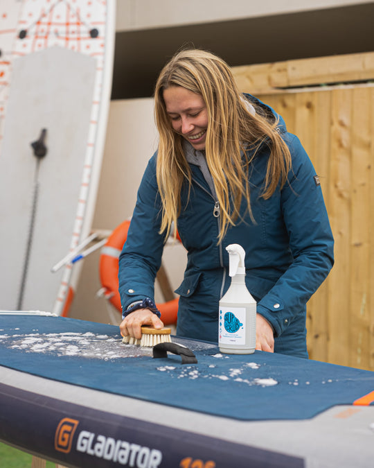 Lady cleaning her Paddleboard with the SUPscrub bamboo brush